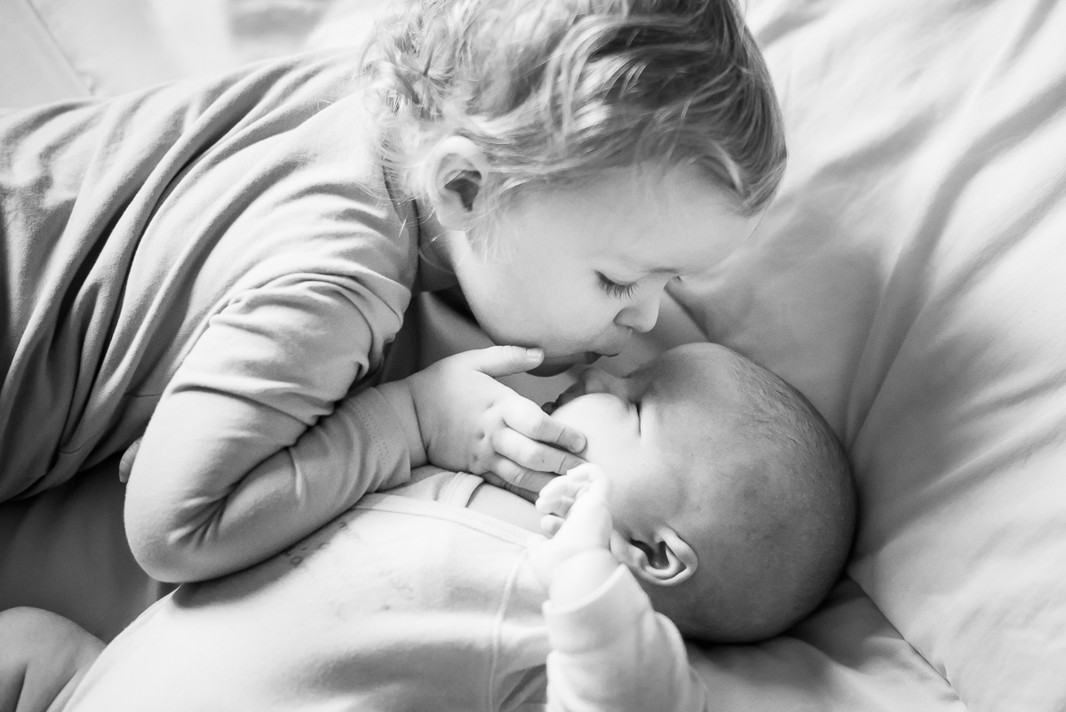 grande soeur faisant un bisou sur le nez de son petit frère photographe bébé Lille